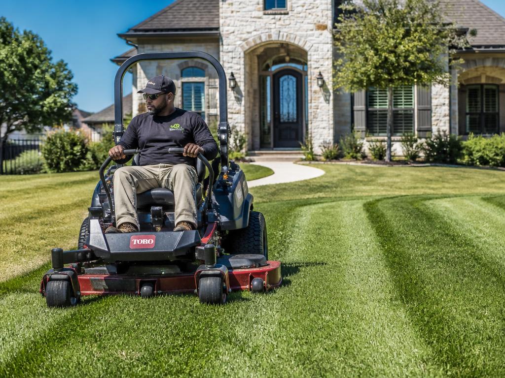 Lawn care professional mowing a manicured residential lawn